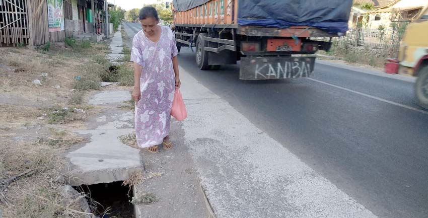 HANCUR : Warga sekitar saat menunjukkan drainase yang rusak berat berlokasi di jalan raya Desa Kotakan serta sering makan korban. (im)