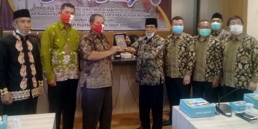 Ketua FKUB Kabupaten Situbondo KH Yusron Samrowi didampingi oleh Kepala Bakesbangpol Edy Wiyono saat memberikan cindera mata kepada Ketua FKUB Jawa Timur (Jatim) A Hamid Syarif di ruang Baluran Pemkab Situbondo. (her)